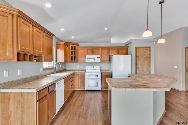 kitchen featuring a center island, sink, tile countertops, and white appliances