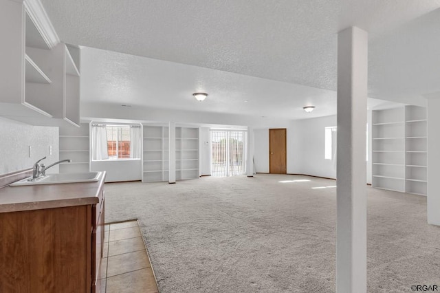 living room with sink, a wealth of natural light, light colored carpet, and a textured ceiling