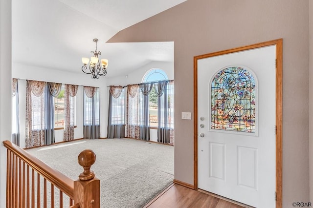 foyer with an inviting chandelier, vaulted ceiling, and light hardwood / wood-style flooring