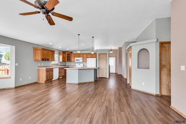 kitchen featuring lofted ceiling, a center island, hanging light fixtures, hardwood / wood-style flooring, and white appliances