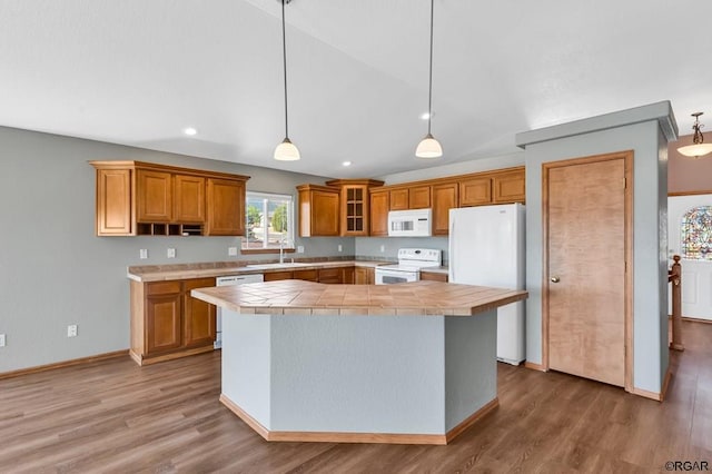 kitchen featuring hardwood / wood-style floors, lofted ceiling, sink, hanging light fixtures, and white appliances