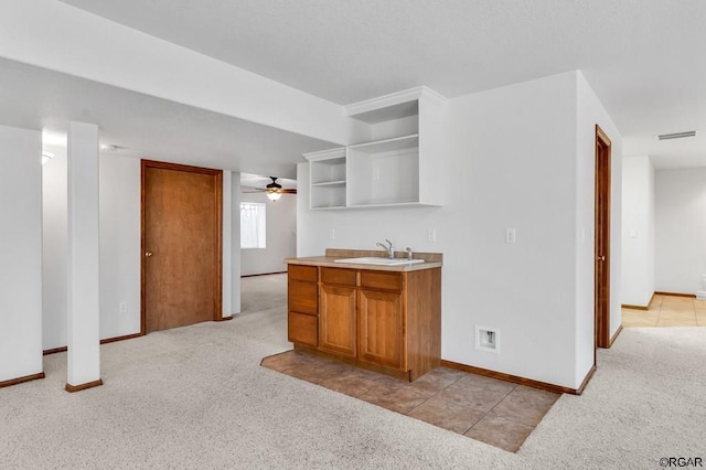 kitchen with sink, light colored carpet, and ceiling fan