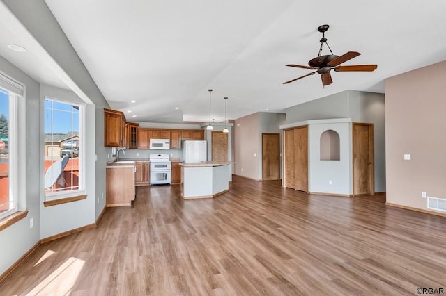 kitchen with a kitchen island, pendant lighting, sink, white appliances, and light hardwood / wood-style flooring