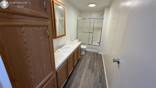 1157 County Road 119, Florence, CO 81226 - full bath featuring vanity, wood finished floors, toilet, baseboards, and shower / bath combination with glass door