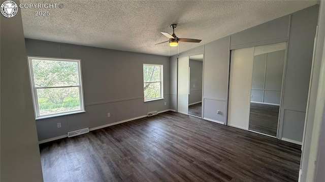 1157 County Road 119, Florence, CO 81226 - unfurnished bedroom with dark wood-style flooring, a textured ceiling, baseboards, ceiling fan, and two closets