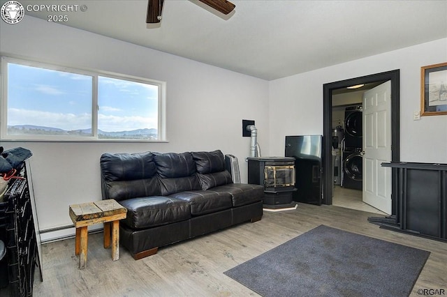 136 Arapahoe Cir, Westcliffe, CO 81252 - living area with stacked washing machine and dryer, wood finished floors, a ceiling fan, and a baseboard radiator