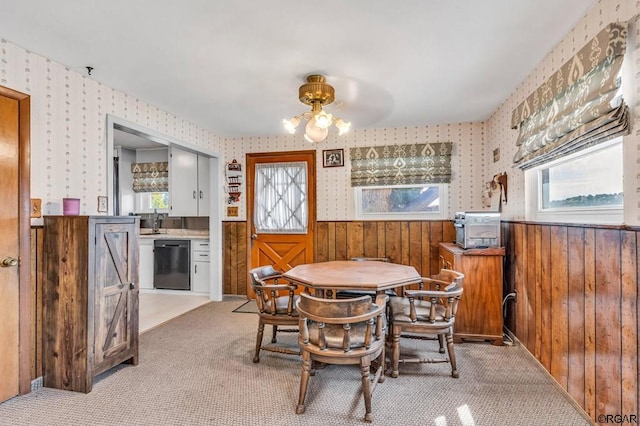 carpeted dining room with plenty of natural light, sink, and wood walls