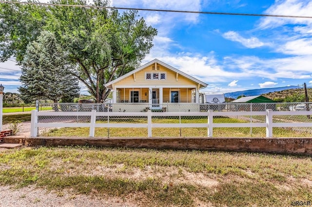 rear view of property featuring a mountain view, covered porch, and a lawn