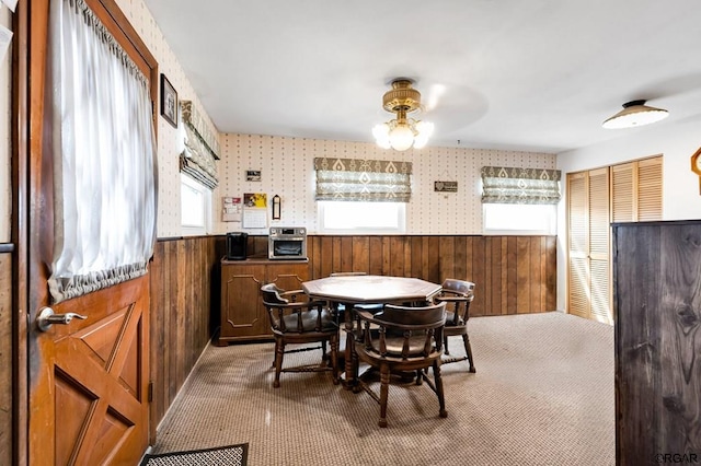 carpeted dining area with wood walls