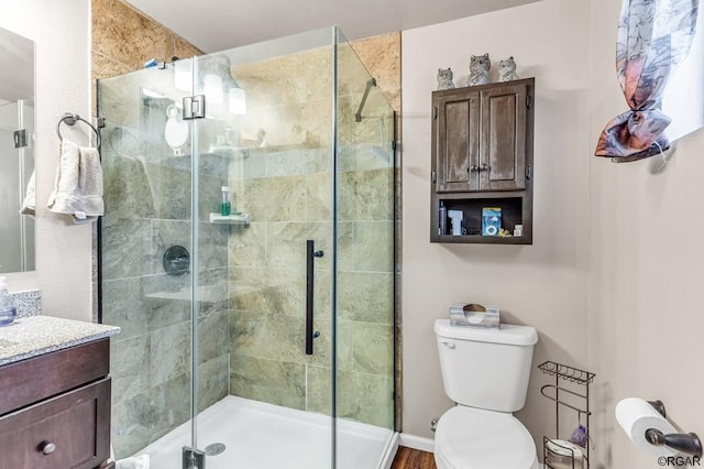 bathroom with toilet, vanity, and a shower with shower door