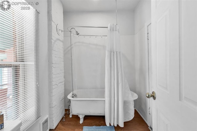 bathroom with hardwood / wood-style flooring and shower / bath combo with shower curtain