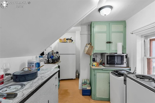 kitchen with electric stove, green cabinetry, and white refrigerator