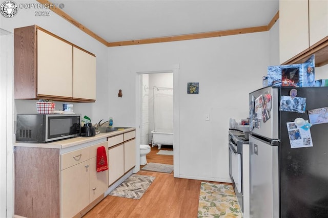 kitchen with sink, crown molding, light hardwood / wood-style flooring, and appliances with stainless steel finishes