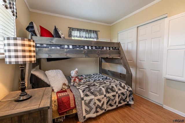 bedroom with multiple windows, crown molding, a closet, and light wood-type flooring