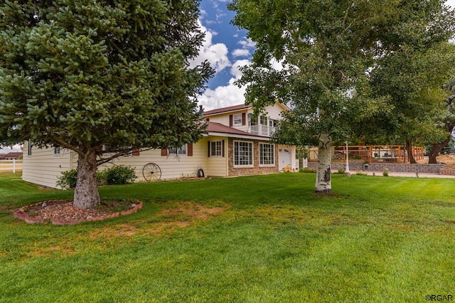 view of front of home featuring a balcony and a front lawn