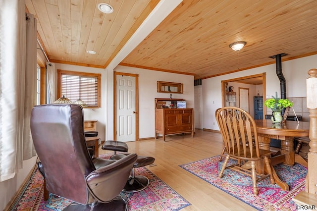 dining room featuring ornamental molding, light hardwood / wood-style floors, a wood stove, and wooden ceiling