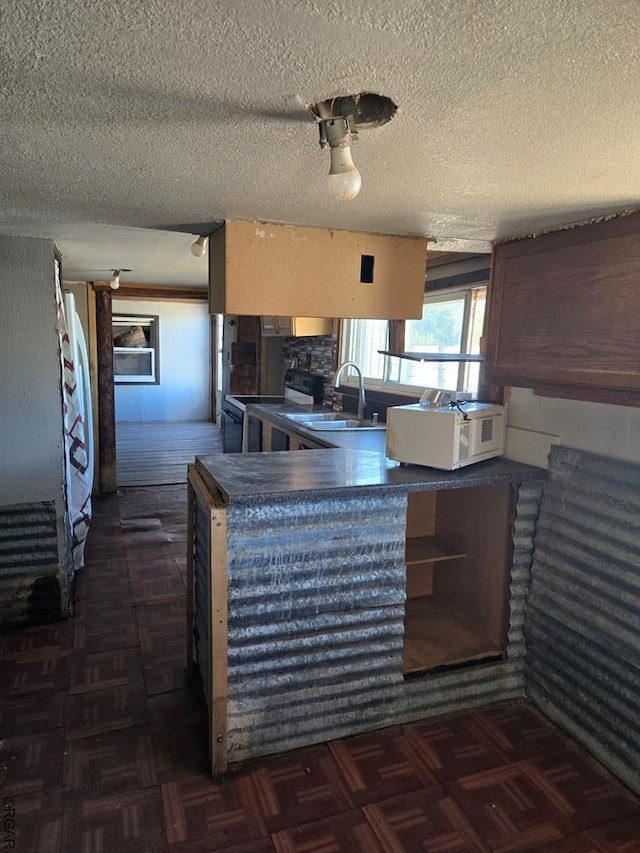 kitchen featuring sink, a textured ceiling, black / electric stove, kitchen peninsula, and dark parquet floors