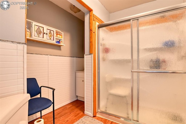 1110 Euclid Ave, Pueblo, CO 81004 - bathroom with wood finished floors, a shower stall, a wainscoted wall, and toilet