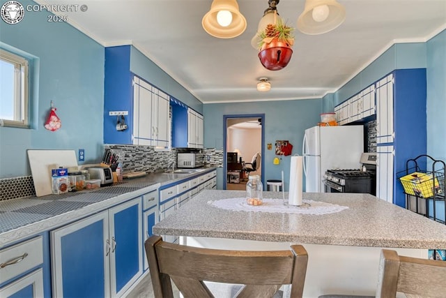 1110 Euclid Ave, Pueblo, CO 81004 - kitchen with stainless steel gas stove, blue cabinets, backsplash, a breakfast bar, and crown molding