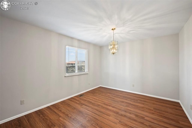 unfurnished room with hardwood / wood-style floors and an inviting chandelier