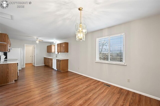 kitchen featuring sink, hanging light fixtures, white dishwasher, dark hardwood / wood-style flooring, and ceiling fan with notable chandelier