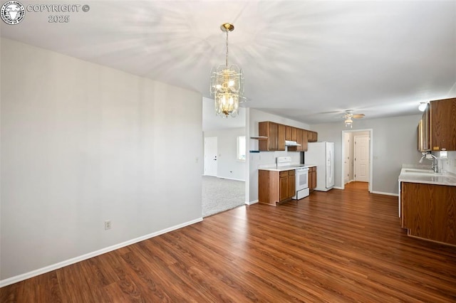 kitchen featuring dark hardwood / wood-style floors, decorative light fixtures, sink, white appliances, and an inviting chandelier