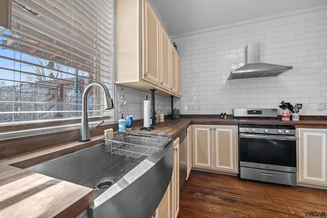 kitchen featuring wall chimney exhaust hood, sink, butcher block countertops, wall oven, and cream cabinets