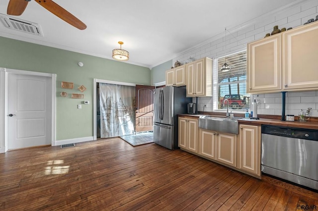 kitchen with sink, crown molding, tasteful backsplash, stainless steel appliances, and cream cabinetry