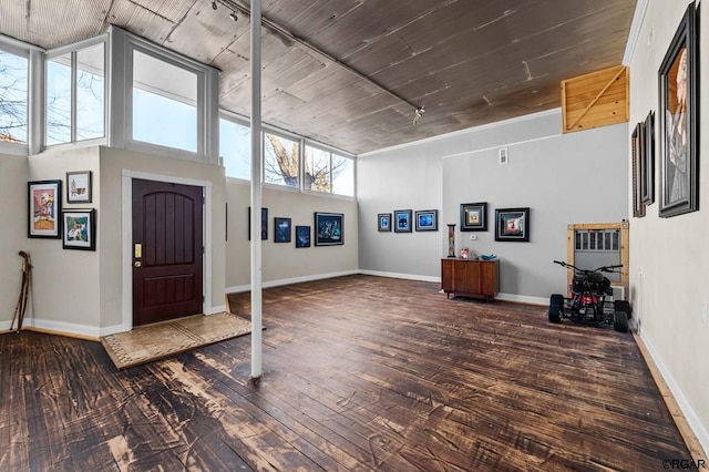 entryway with dark wood-type flooring and a towering ceiling