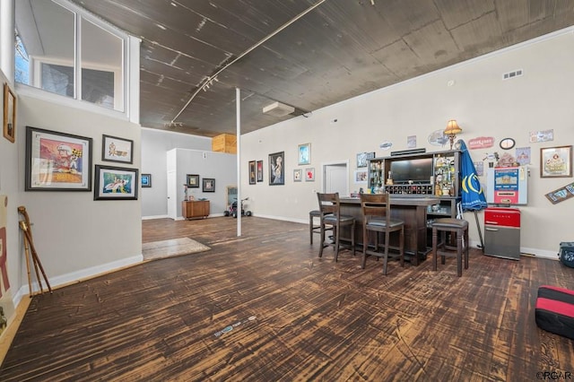 dining space with a high ceiling, indoor bar, and dark carpet