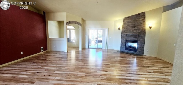 unfurnished living room featuring a fireplace, wood finished floors, visible vents, and baseboards