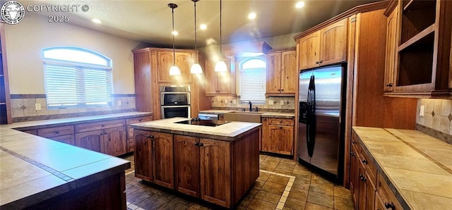 kitchen with recessed lighting, stainless steel appliances, a sink, a kitchen island, and hanging light fixtures