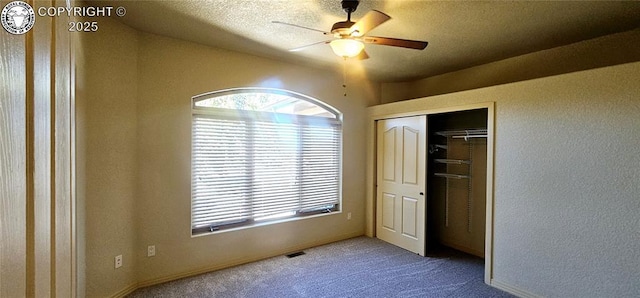 unfurnished bedroom featuring a textured ceiling, carpet floors, visible vents, a ceiling fan, and a closet