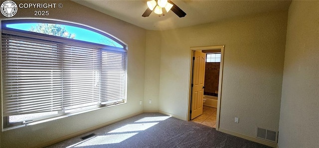 unfurnished room with plenty of natural light, visible vents, and carpet flooring