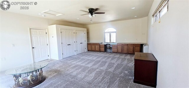 interior space with attic access, light colored carpet, and a ceiling fan