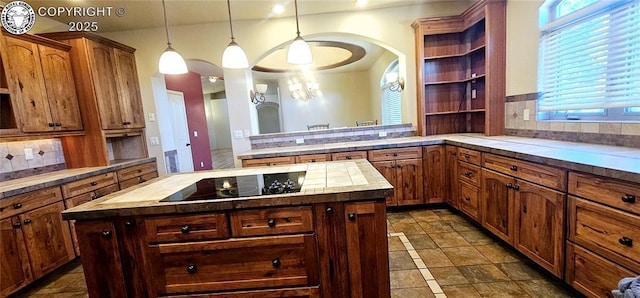 kitchen featuring decorative backsplash, pendant lighting, a kitchen island, and black electric stovetop