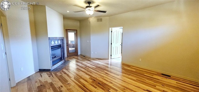 unfurnished living room with baseboards, visible vents, ceiling fan, light wood-style floors, and a fireplace