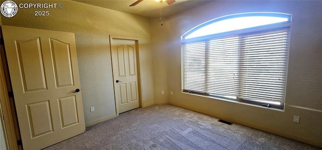 unfurnished bedroom featuring carpet floors, baseboards, visible vents, and ceiling fan