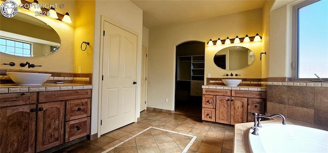 full bath featuring a bath, two vanities, a sink, and tile patterned floors