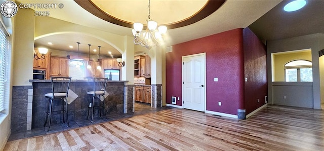 kitchen with a breakfast bar area, appliances with stainless steel finishes, a raised ceiling, and wood finished floors