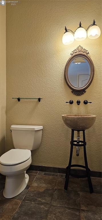 half bath featuring a textured wall and toilet