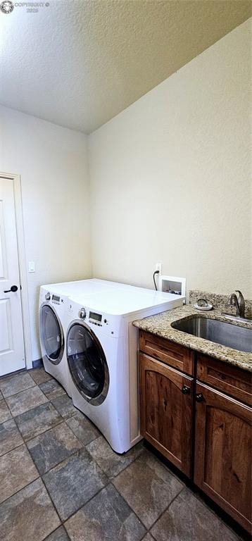 laundry area with cabinet space, independent washer and dryer, stone finish flooring, a textured ceiling, and a sink