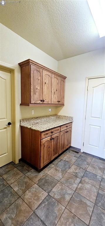 kitchen with baseboards, brown cabinets, and a textured ceiling