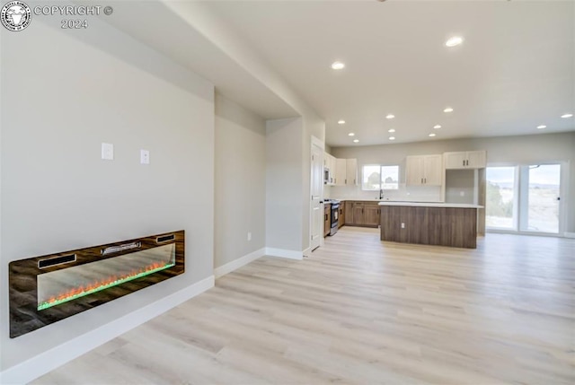 unfurnished living room featuring a wealth of natural light and light hardwood / wood-style floors