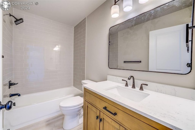 full bathroom with tiled shower / bath, vanity, and toilet