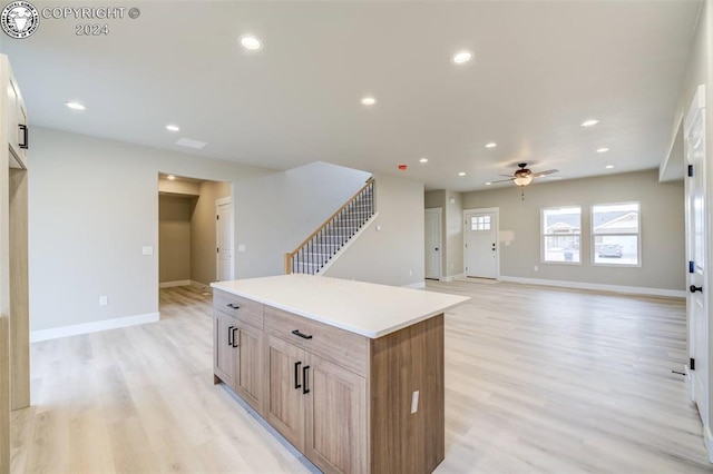 kitchen featuring light brown cabinetry, a center island, ceiling fan, and light wood-type flooring