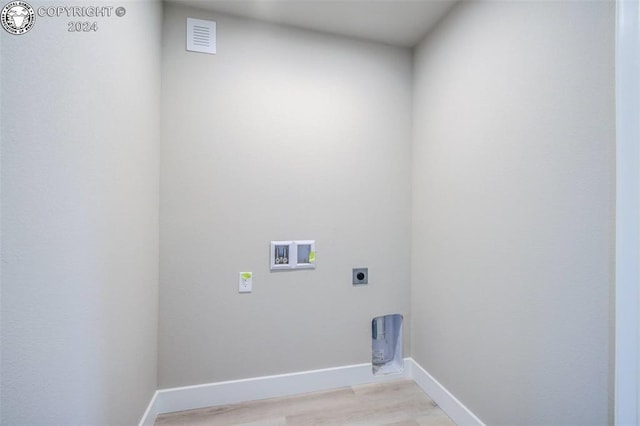 clothes washing area with hookup for an electric dryer, hookup for a washing machine, and light wood-type flooring