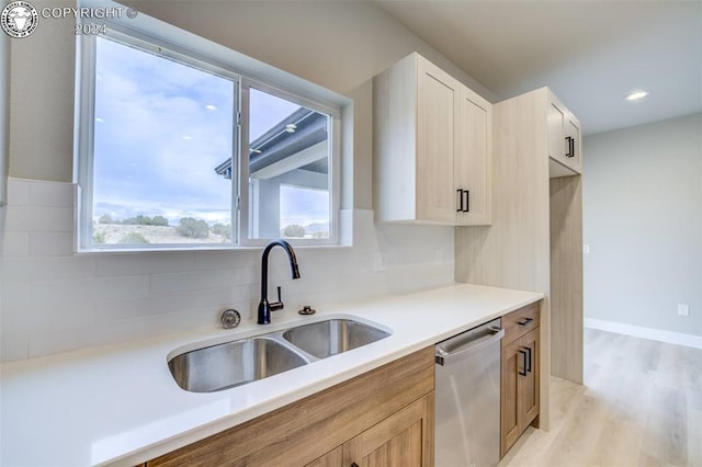 kitchen featuring tasteful backsplash, dishwasher, sink, and light hardwood / wood-style flooring