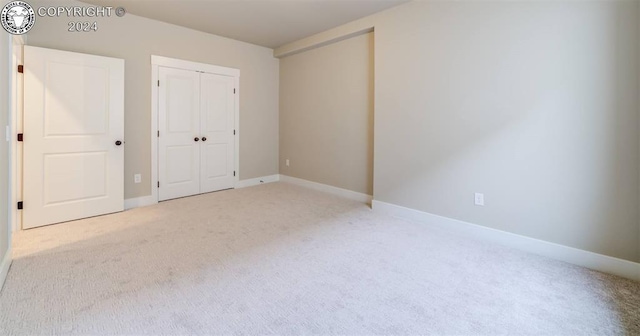 unfurnished bedroom featuring light carpet and a closet