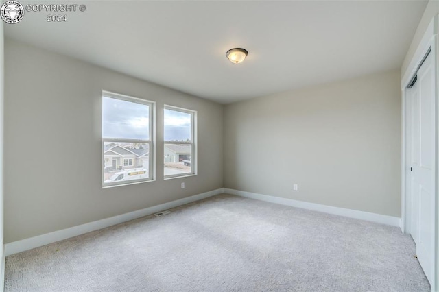 unfurnished bedroom featuring light colored carpet and a closet